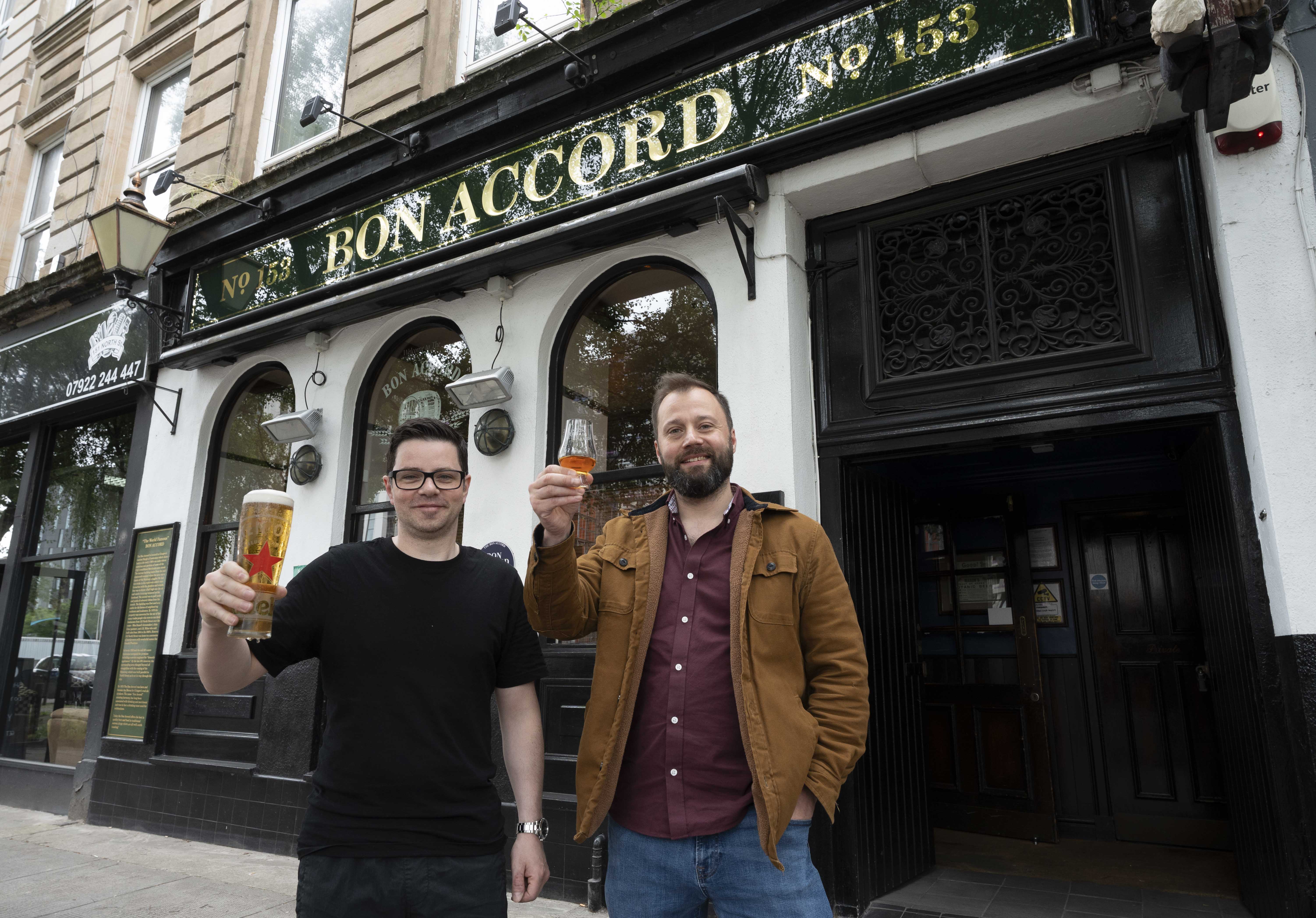Two male pub licensees standing outside the Bon Accord pub in Glasgow