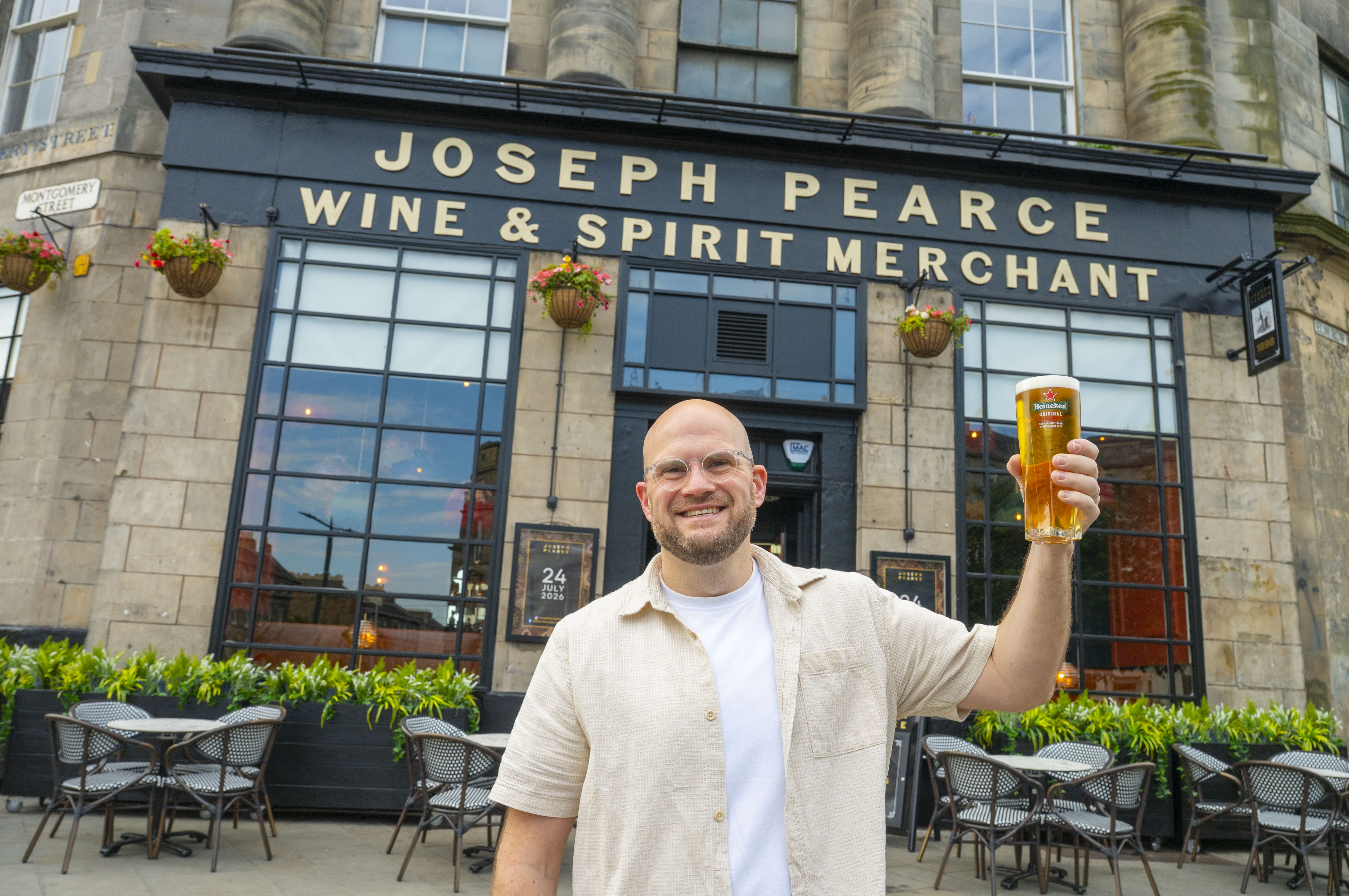 Joseph Pearce pub with operator standing outside holding a pint of beer