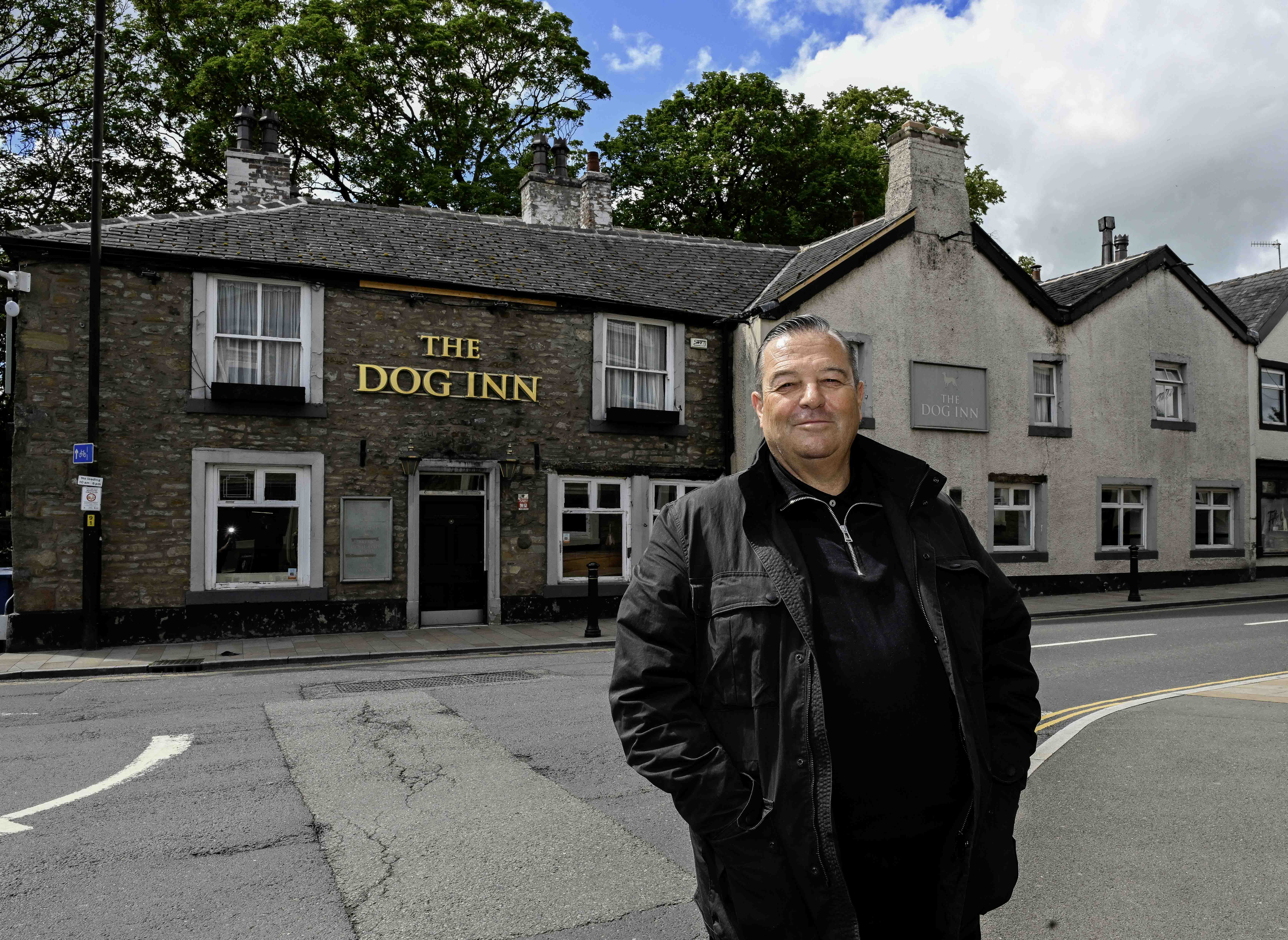 Man standing outside of The Dog Inn pub