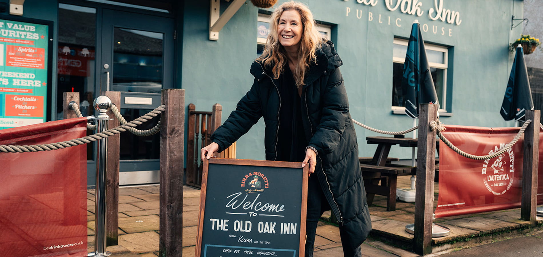 Woman opening up her pub setting out advertising board