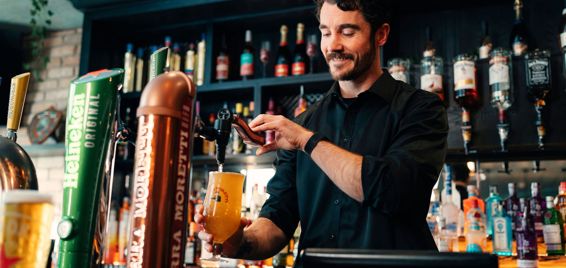 A man learning to pull a pint in a pub