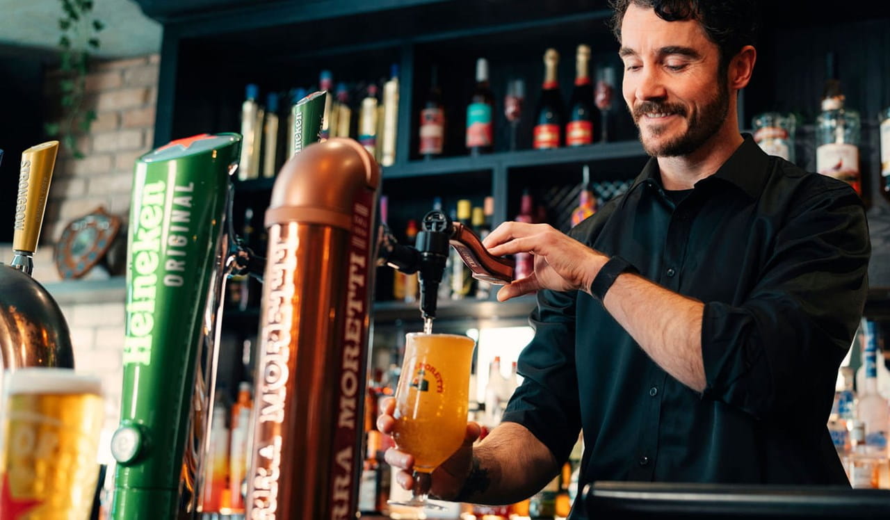 A man learning to pull a pint in a pub