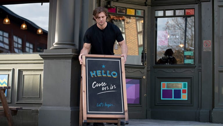 Man placing sandwich board outside pub