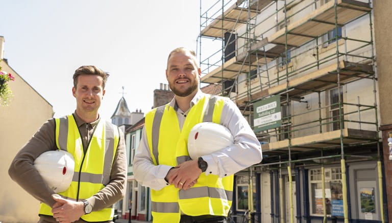 Pub operators standing outside a pub in North Berwick wearing hi-vis jackets and holding hard hats