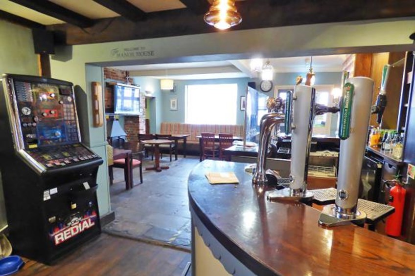 Bar area with games machine and sitting area with tables and chairs